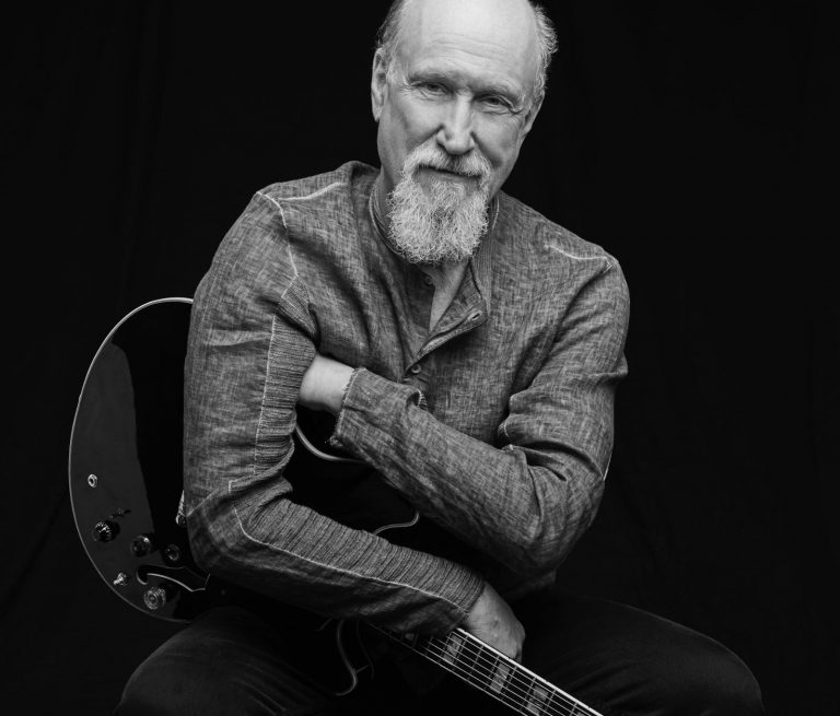Smiling john Scofield with his guitar in arms