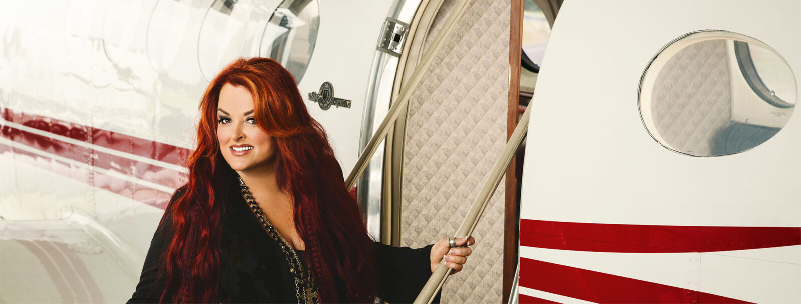 Wynonna, a red hair woman entering an airplane and smiling