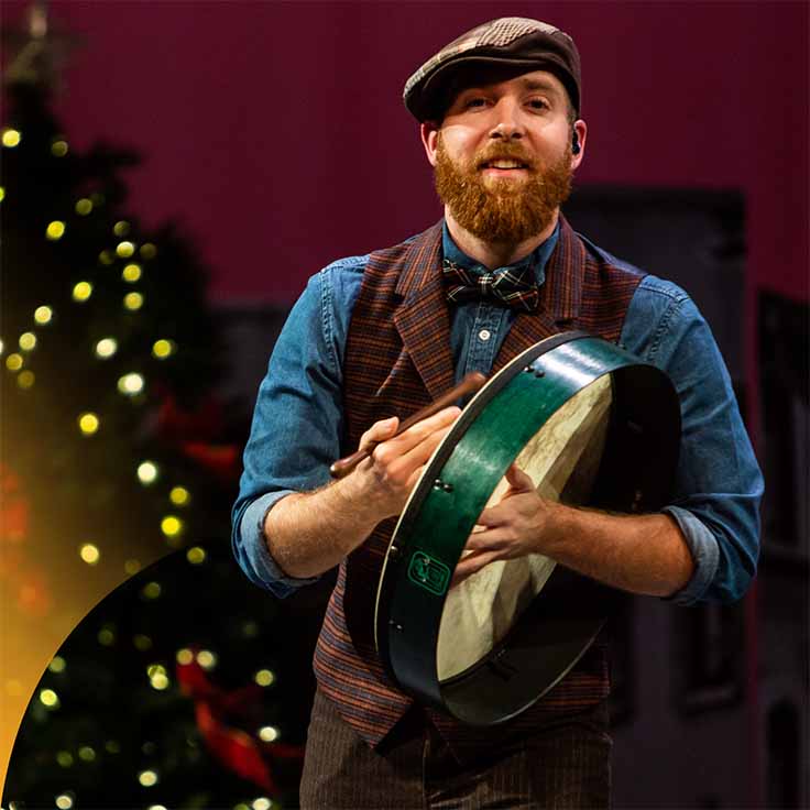 An Irish dancer with a music instrument and a Christmas tree in the background