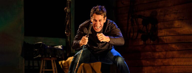 Robert Montano playing jockey, sans the horse, on a wooden stage