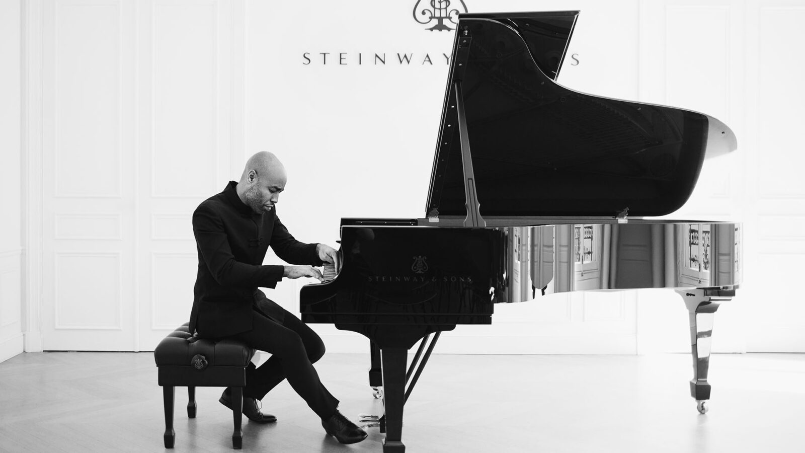 Black and white photo of Aaron Diehl playing a Steinway piano with the logo of the company on the back