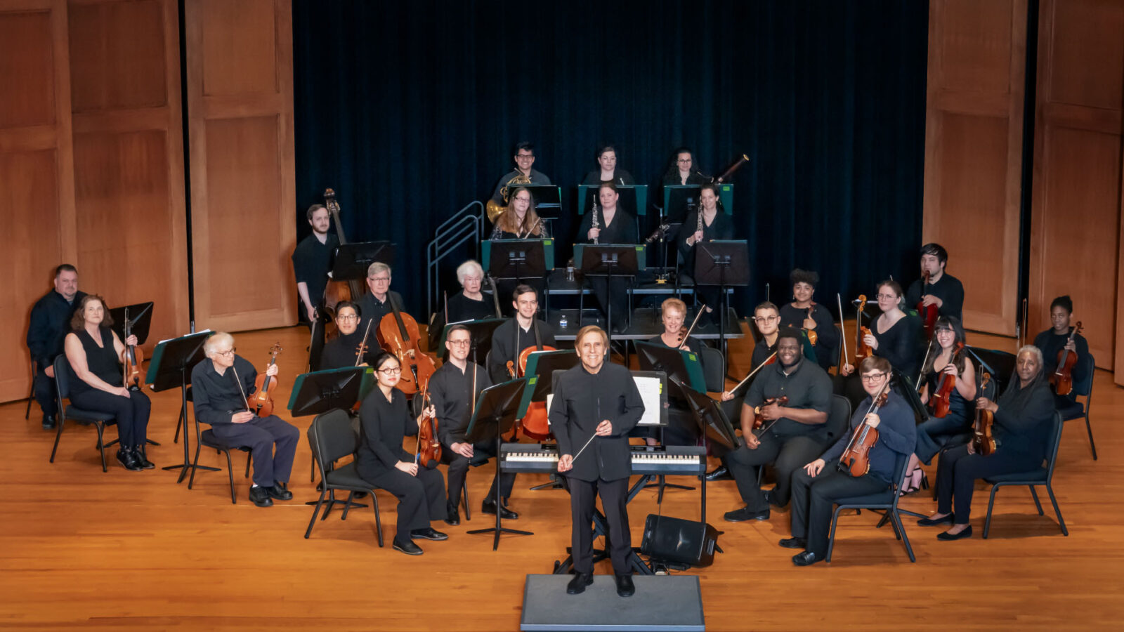 An orchestra on stage with a conductor in the front