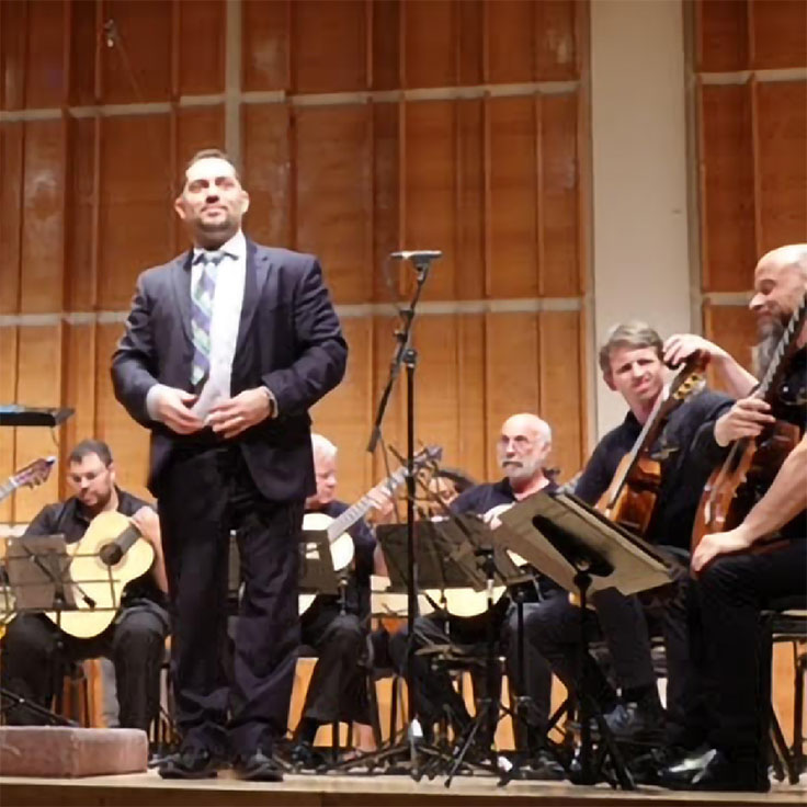 A man standing in front of a regional guitar ensemble