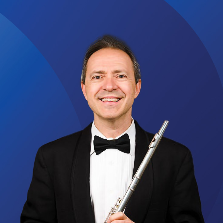 Man in a suit with a flute in hand, smiling. Dark blue background