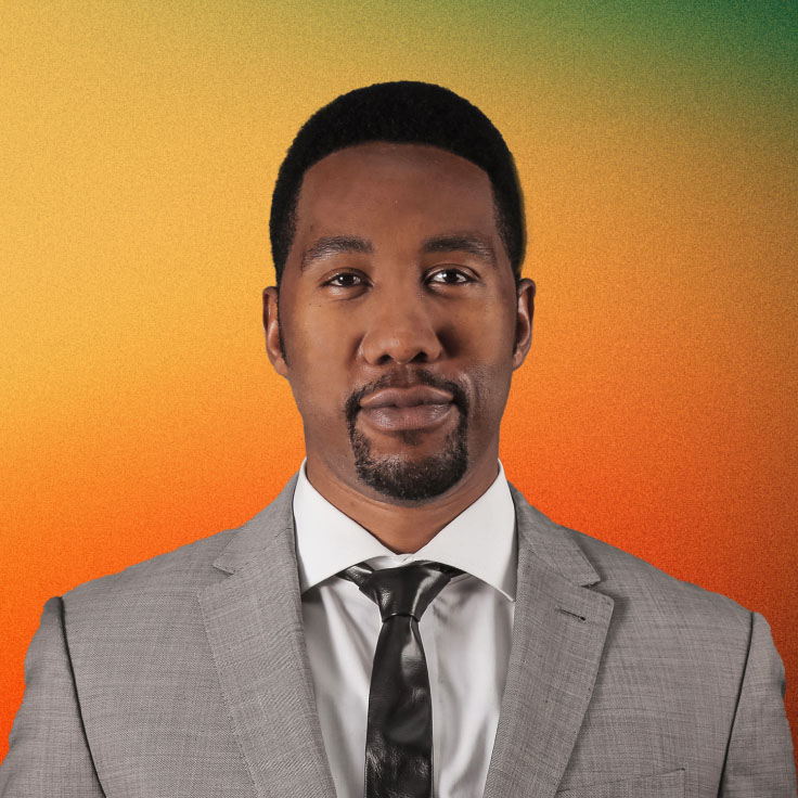 Portrait of Ndaba Mandela, grandson of Nelson Mandela, wearing a light grey suit, white shirt, and a dark tie. He has a short beard and mustache, and stands against a gradient background transitioning from orange to green.