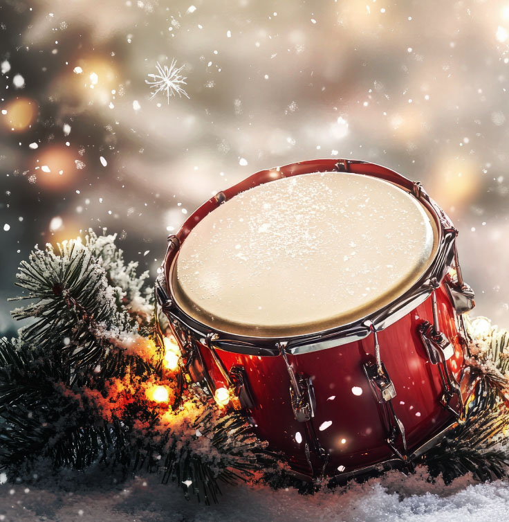 A red drum in the snow surrounded by holiday lights and pine trees