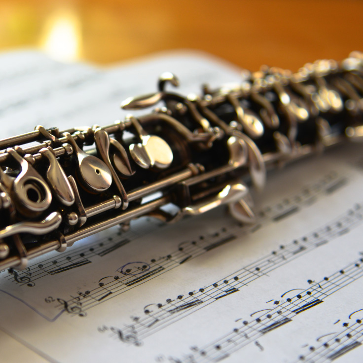 An oboe on top of music sheets on a wooden surface