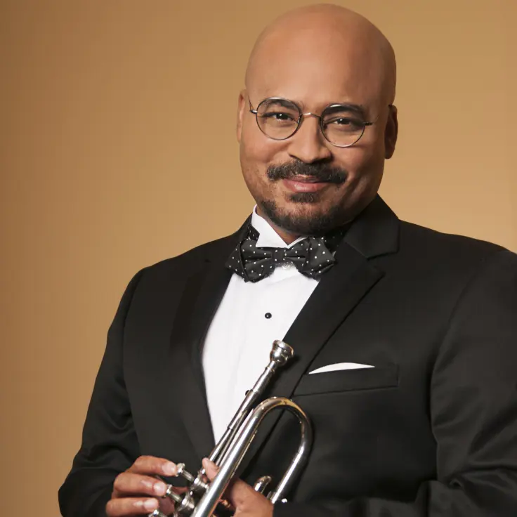 A distinguished musician stands poised in a sharp black tuxedo, complete with a polka-dot bow tie. Glasses rest on the musician's face, offering an intellectual touch. The musician holds a gleaming trumpet, which suggests an affinity for jazz or classical music.
