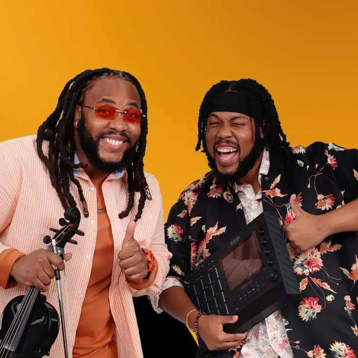 Two musicians smiling and giving thumbs up against an orange curve background